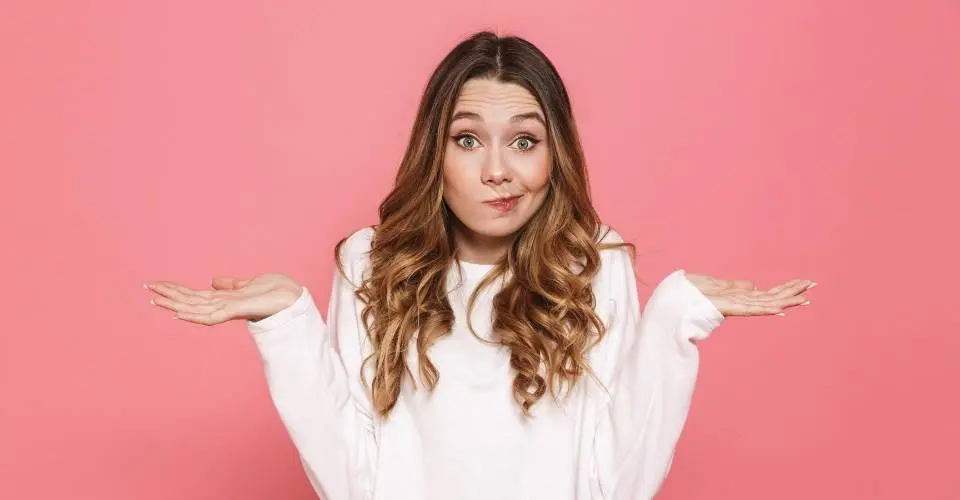 agencia-de-outbound-marketing Mulher jovem com expressão de dúvida e braços levantados, ilustrando a indecisão comum em empresas antes de contratar uma agência de outbound marketing.