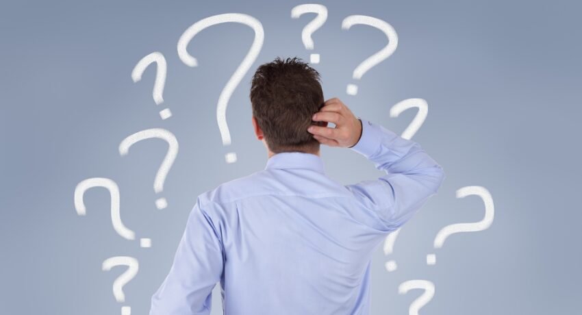 Homem de costas coçando a cabeça diante de vários pontos de interrogação, representando dúvidas comuns na jornada do cliente durante a fase de consideração.