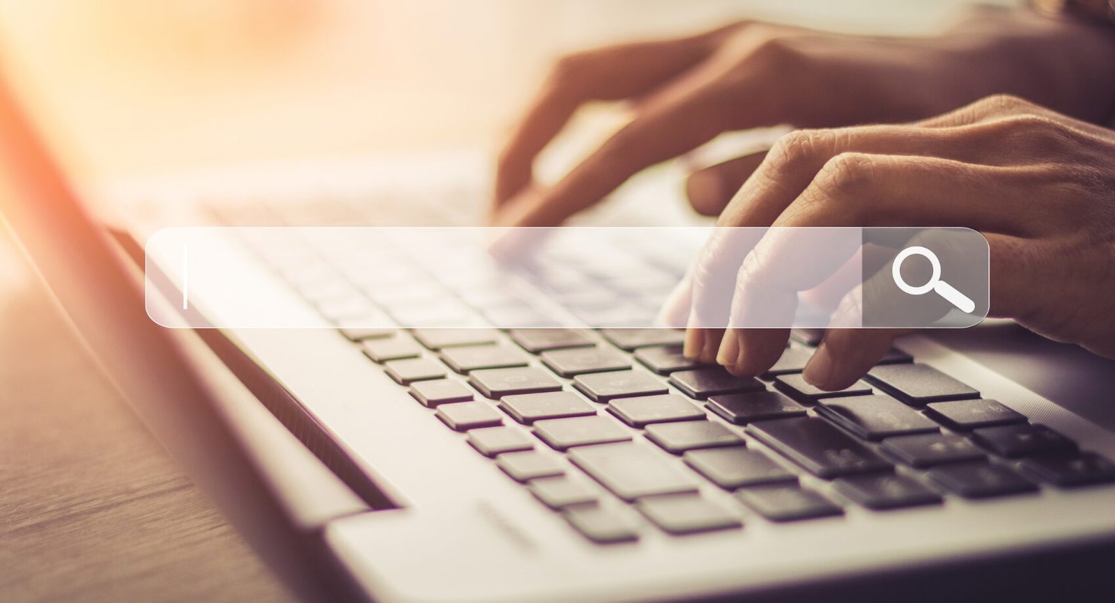 Mãos digitando em um notebook com uma barra de busca sobreposta, representando mudanças no comportamento de busca em 2025 impulsionadas por IA e Google.