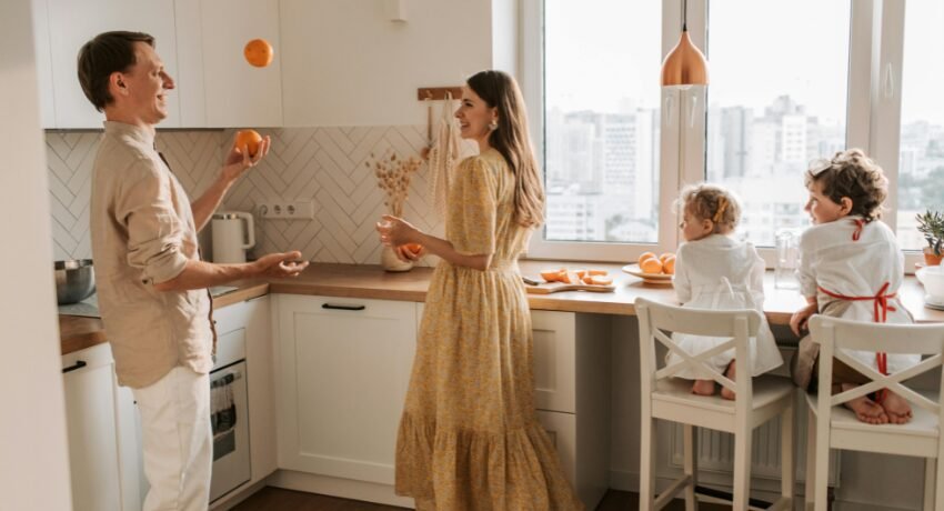Família alegre brincando e interagindo em uma cozinha moderna e bem iluminada.