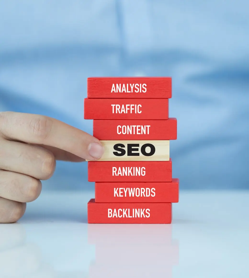 Blocos empilhados representando pilares do SEO, com a palavra SEO no centro e termos como análise, tráfego, conteúdo, ranking, palavras-chave e backlinks.