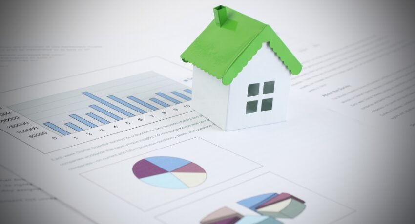 Casa em miniatura sobre gráficos financeiros representando estratégias de marketing de luxo e autoridade em Dubai